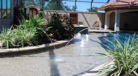custom-gunite-pool-tanning-ledge-with-pebble-plaster-finish-bubblers-laminar-jets-tropical-landscaping